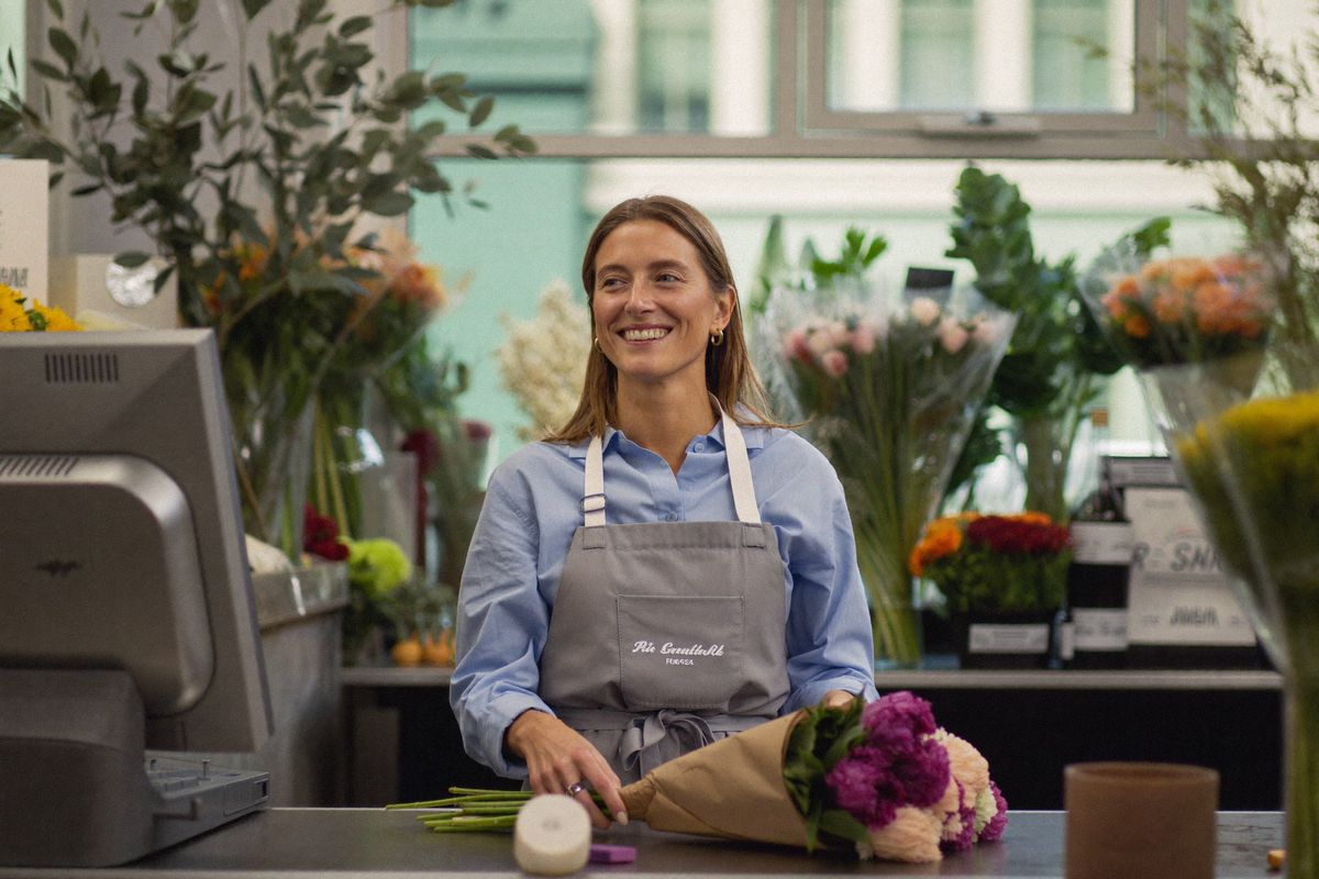 Fleuriste souriante dans sa boutique, une reconversion réussie après un bilan de compétences